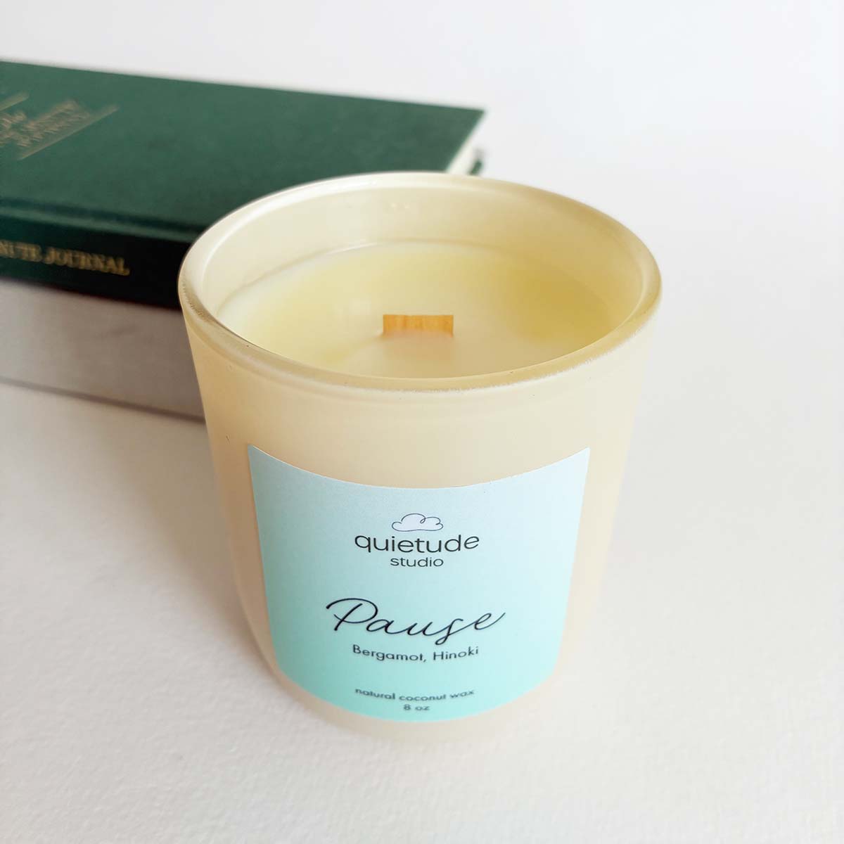 Candle with a quietude studio label on a light surface