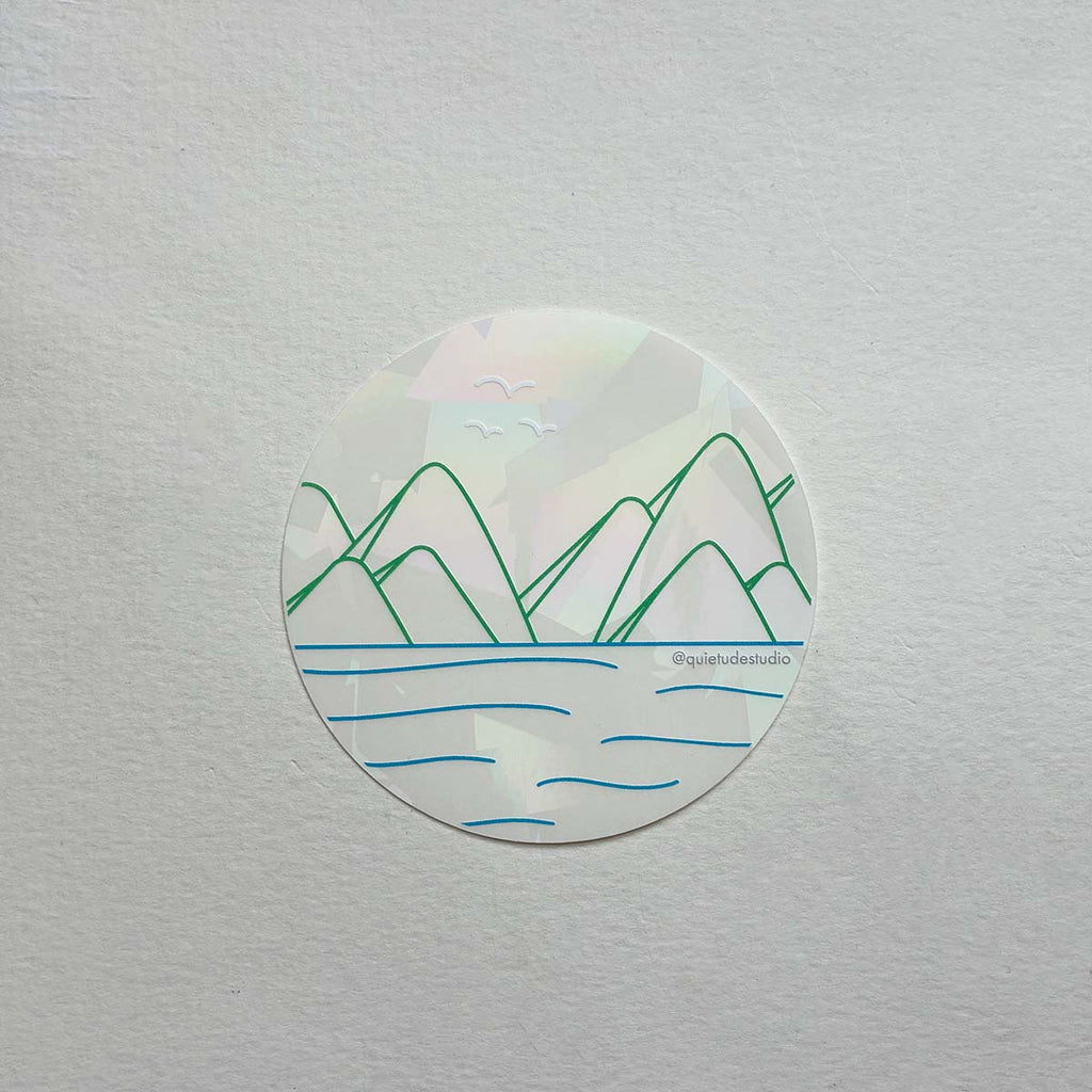 Round suncatcher vinyl sticker with mountain and water design on a white background
