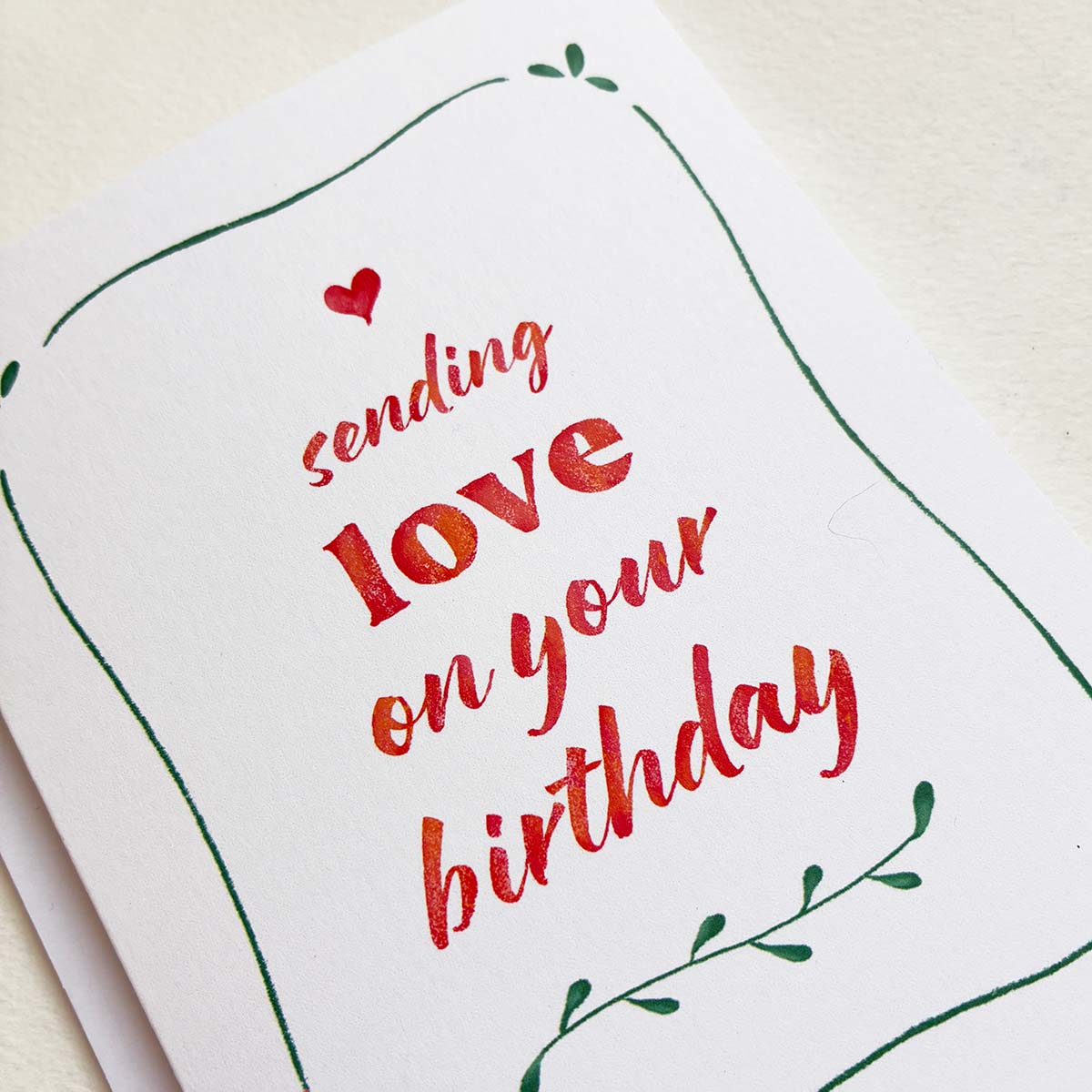 Greeting card with red text 'sending love on your birthday' on a white background
