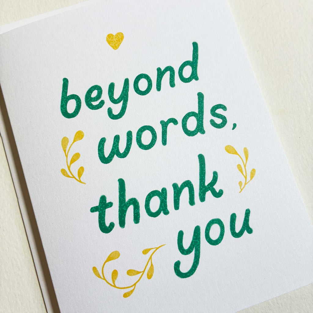 Card with 'beyond words, thank you' text in green with yellow accents on a white background
