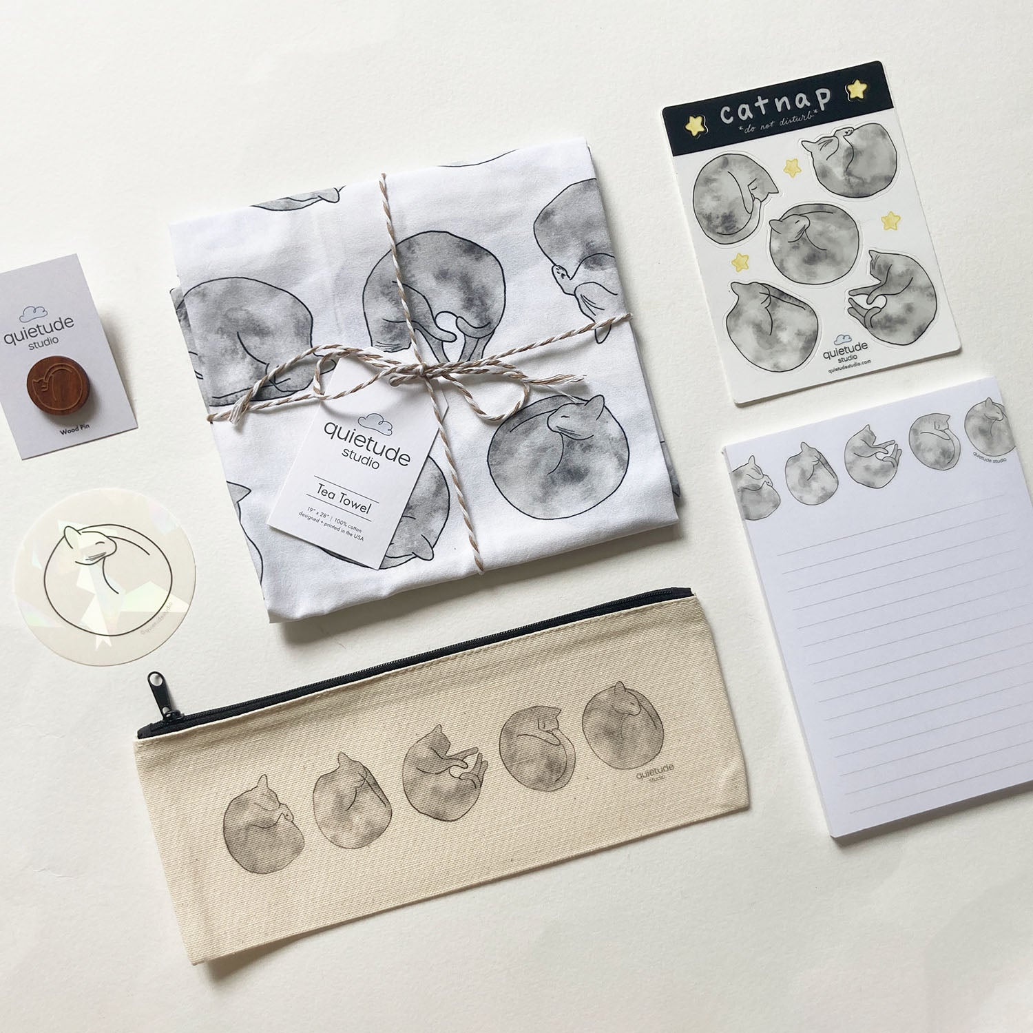 Collection of cat-themed products including a towel, pouch, and notepad on a white background.
